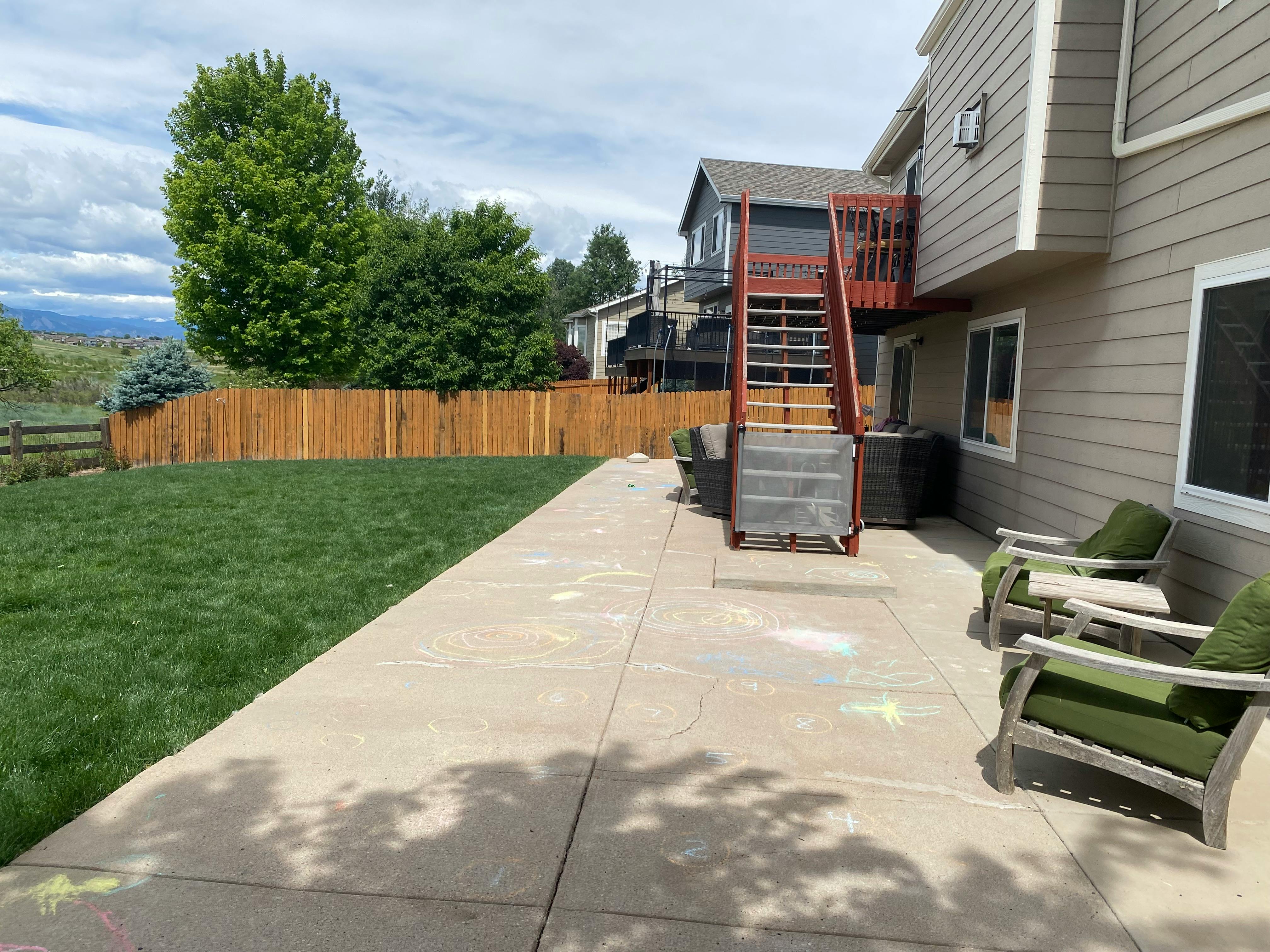 Backyard patio with stairs leading to a second-story deck