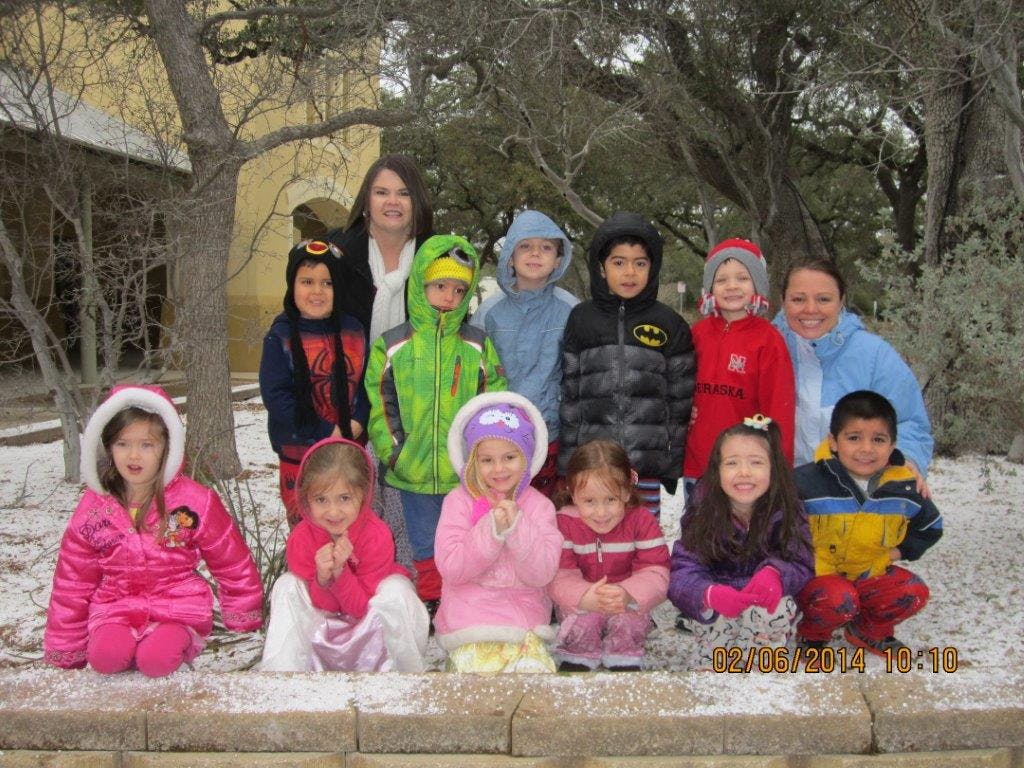 Two people and multiple children in winter coats posing outdoors