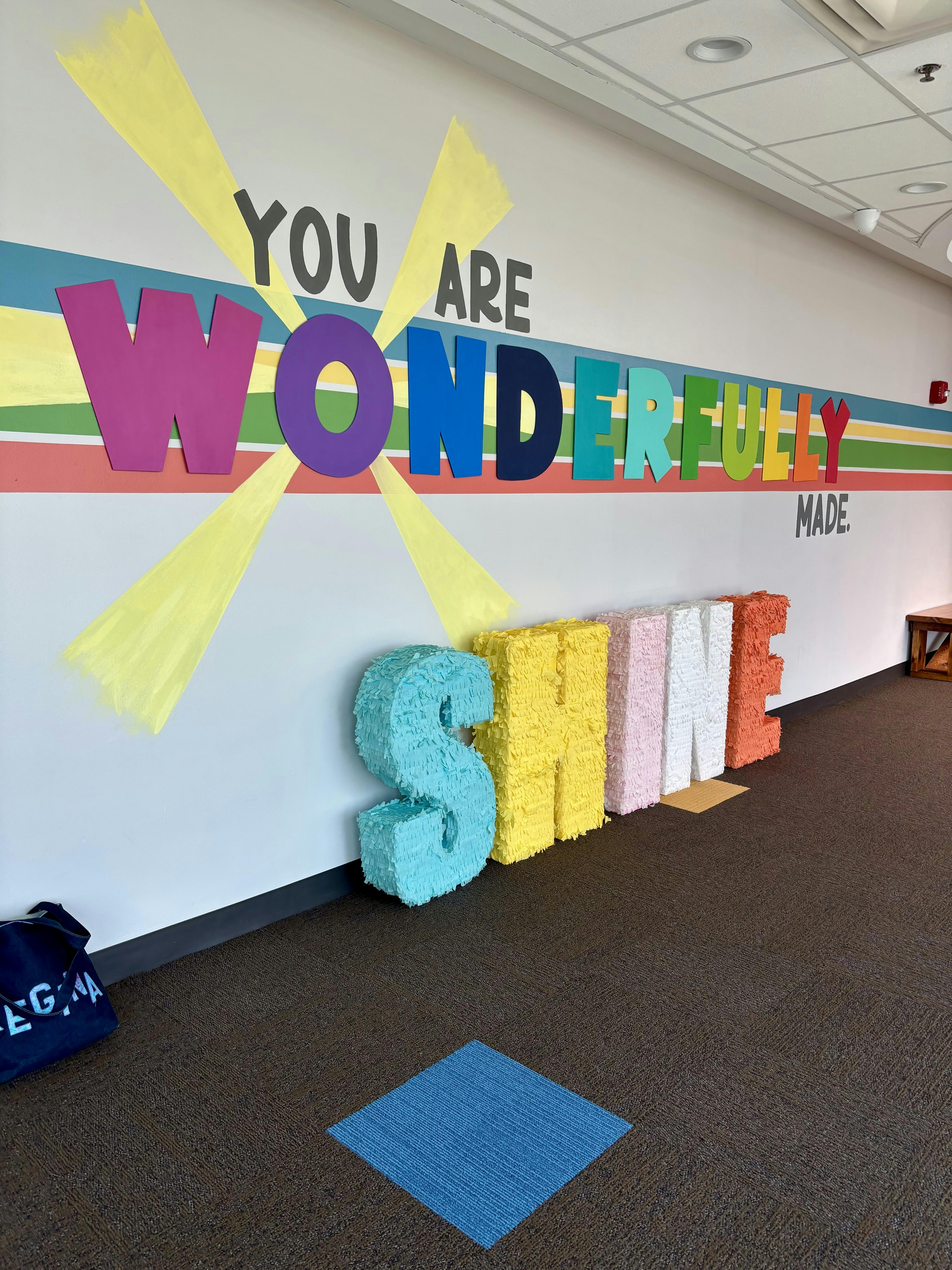 Wall display with the text You Are Wonderfully Made and free-standing SHINE sign
