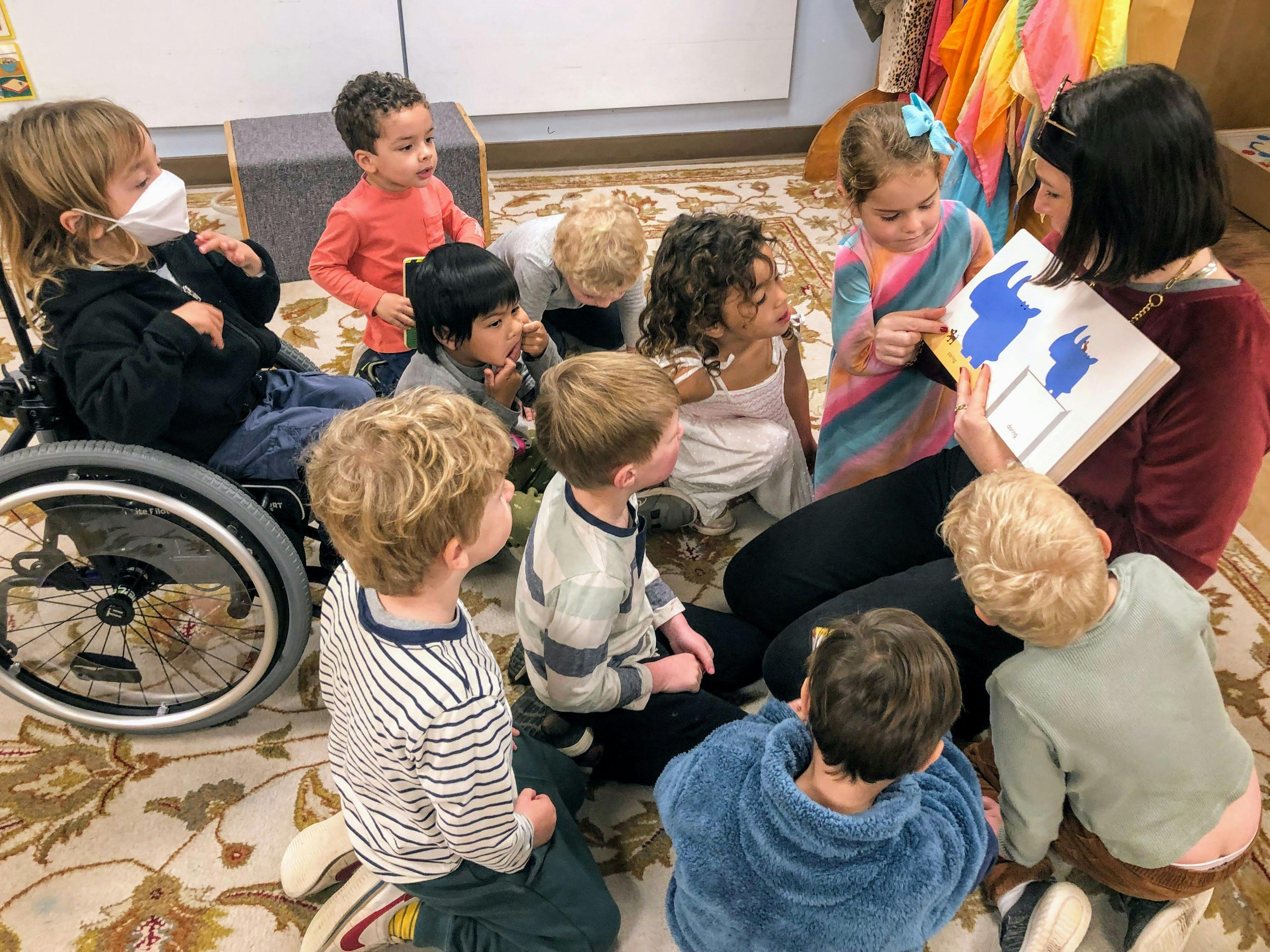Person reading a book to a group of children