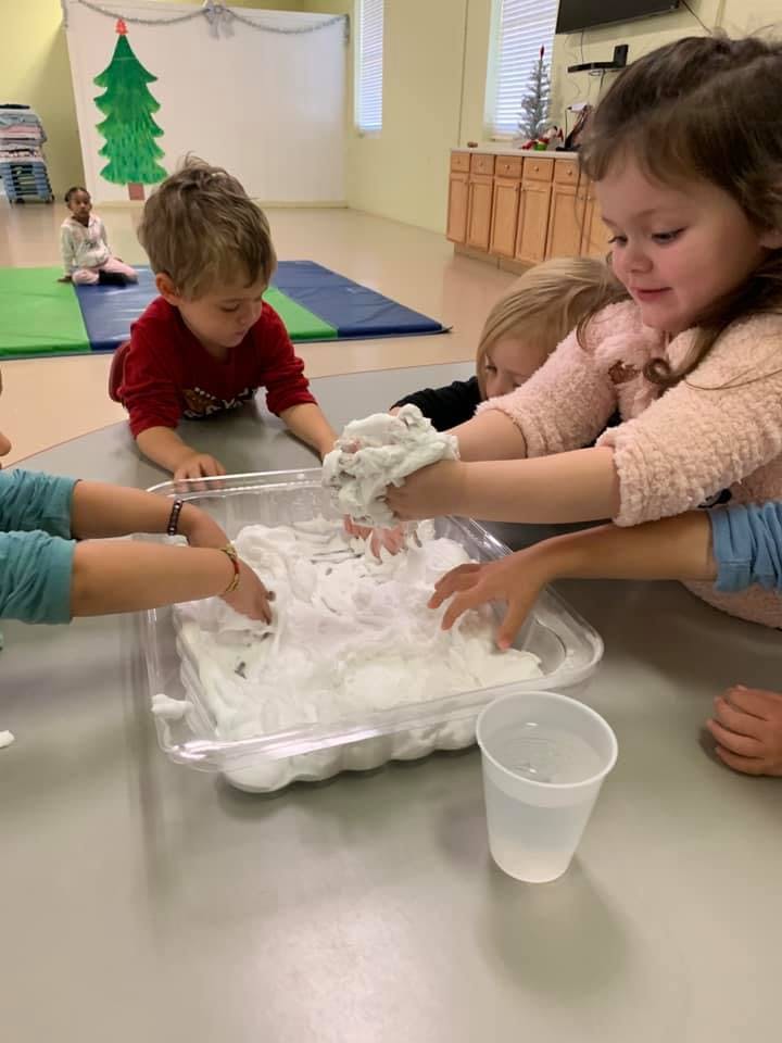 Children playing with a white foamy substance in a clear bin
