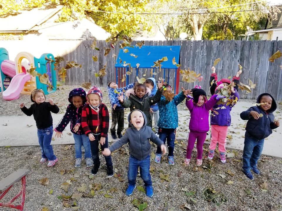 Children playing outdoors with falling leaves
