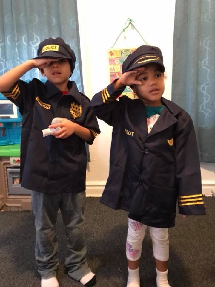 Two children in dress-up uniforms saluting