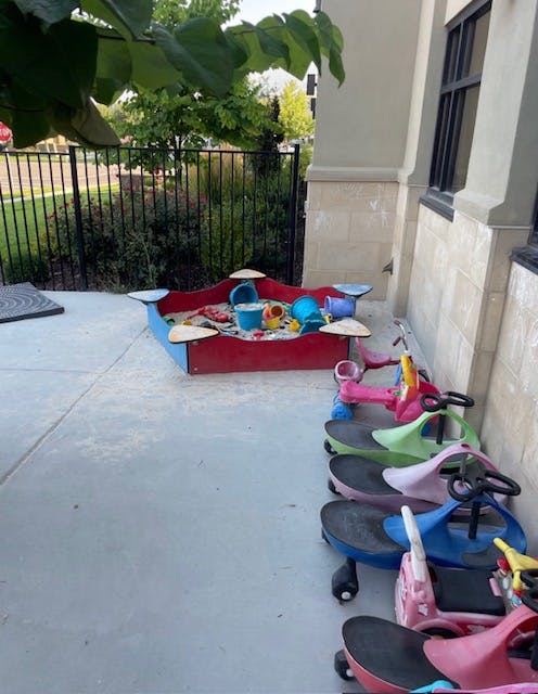 Sandbox with toys and multiple children's ride-on toys lined up
