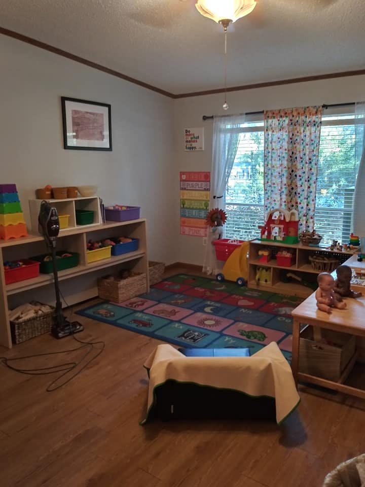 A room with shelves of toys, a colorful rug, and a window with blinds