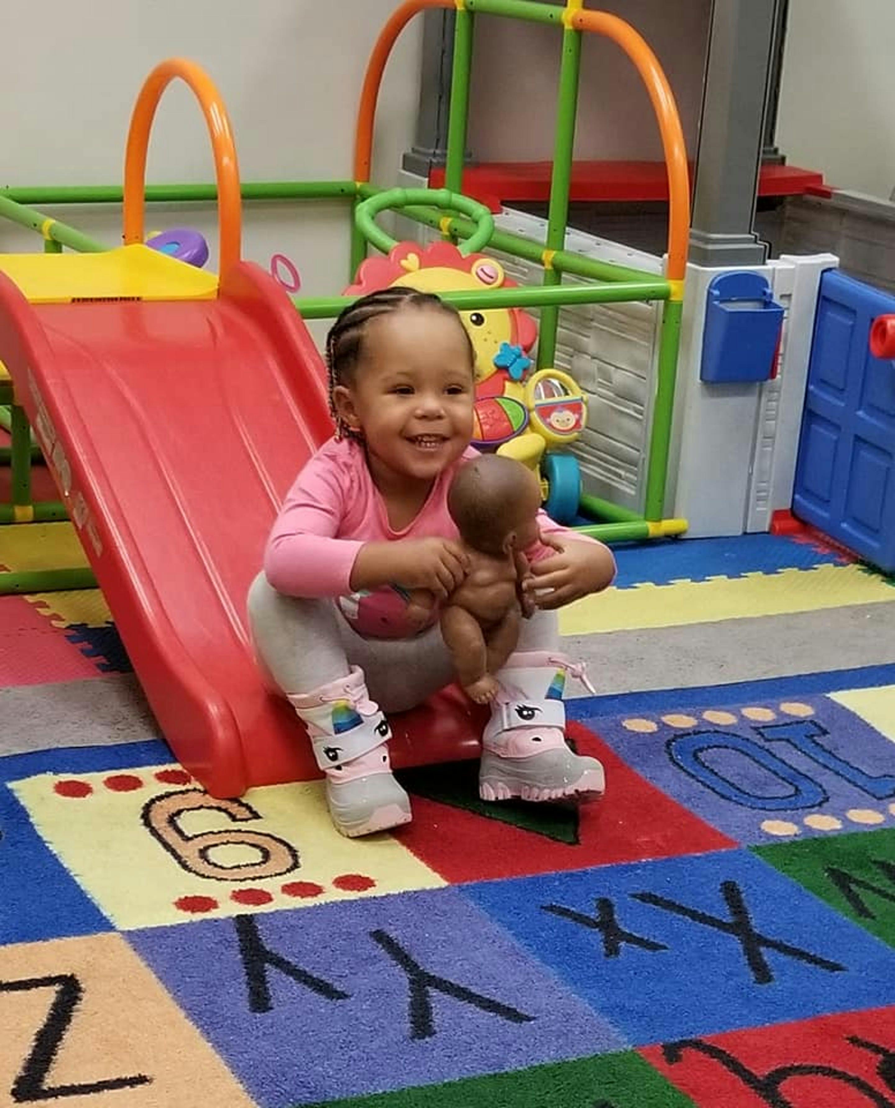 Child holding a doll next to a red slide