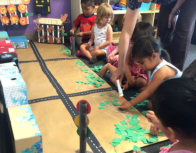Children and an adult creating a road and landscape on the floor