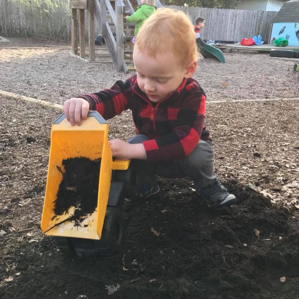 Child playing with a toy truck in dirt