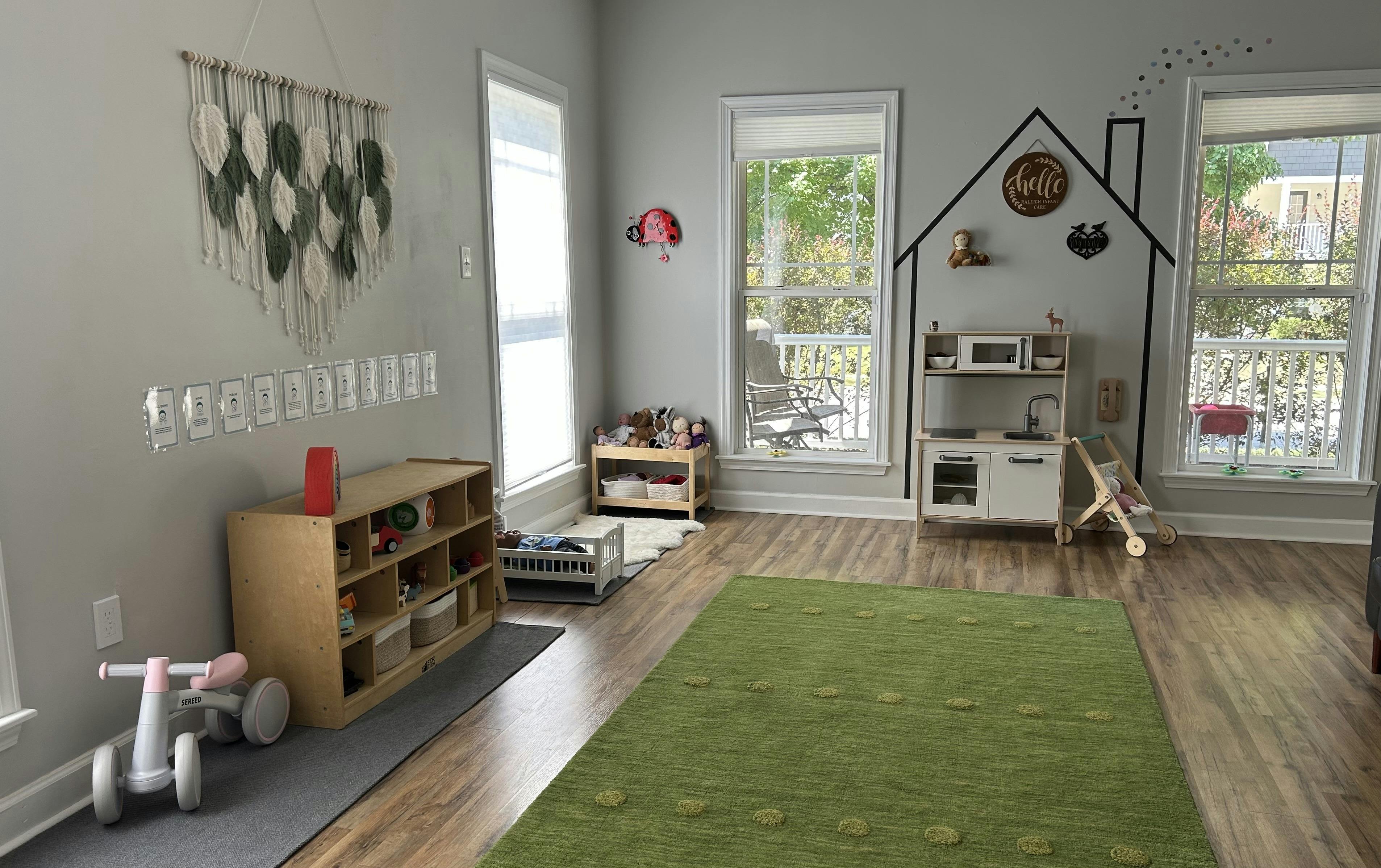 Playroom with wooden toy shelves, a toy kitchen, and a green area rug