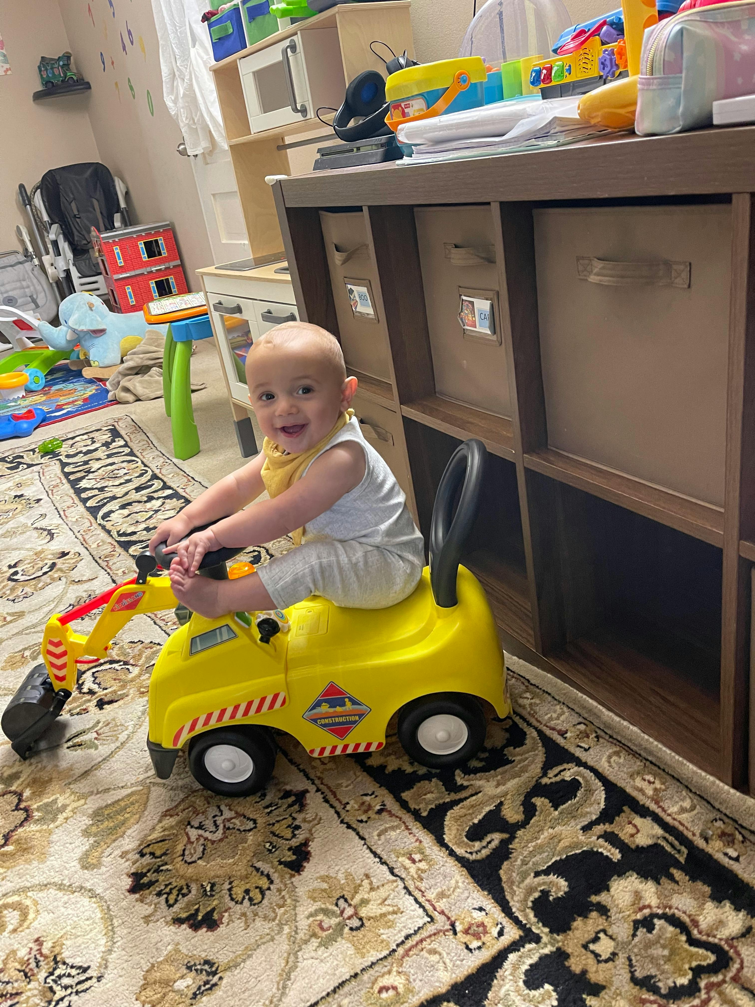 Child sitting on a yellow ride-on toy excavator