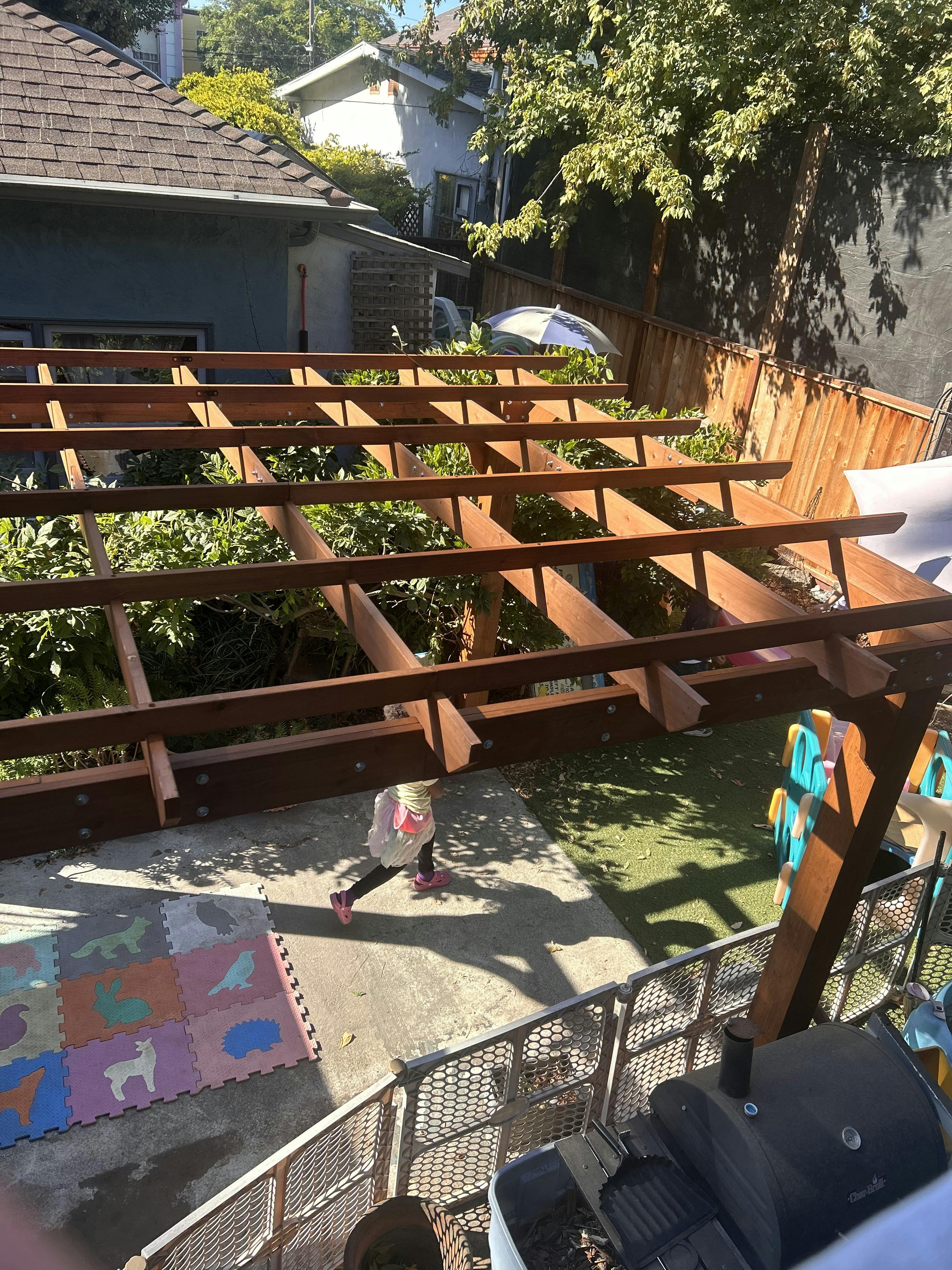 Child walking in a backyard with a wooden pergola