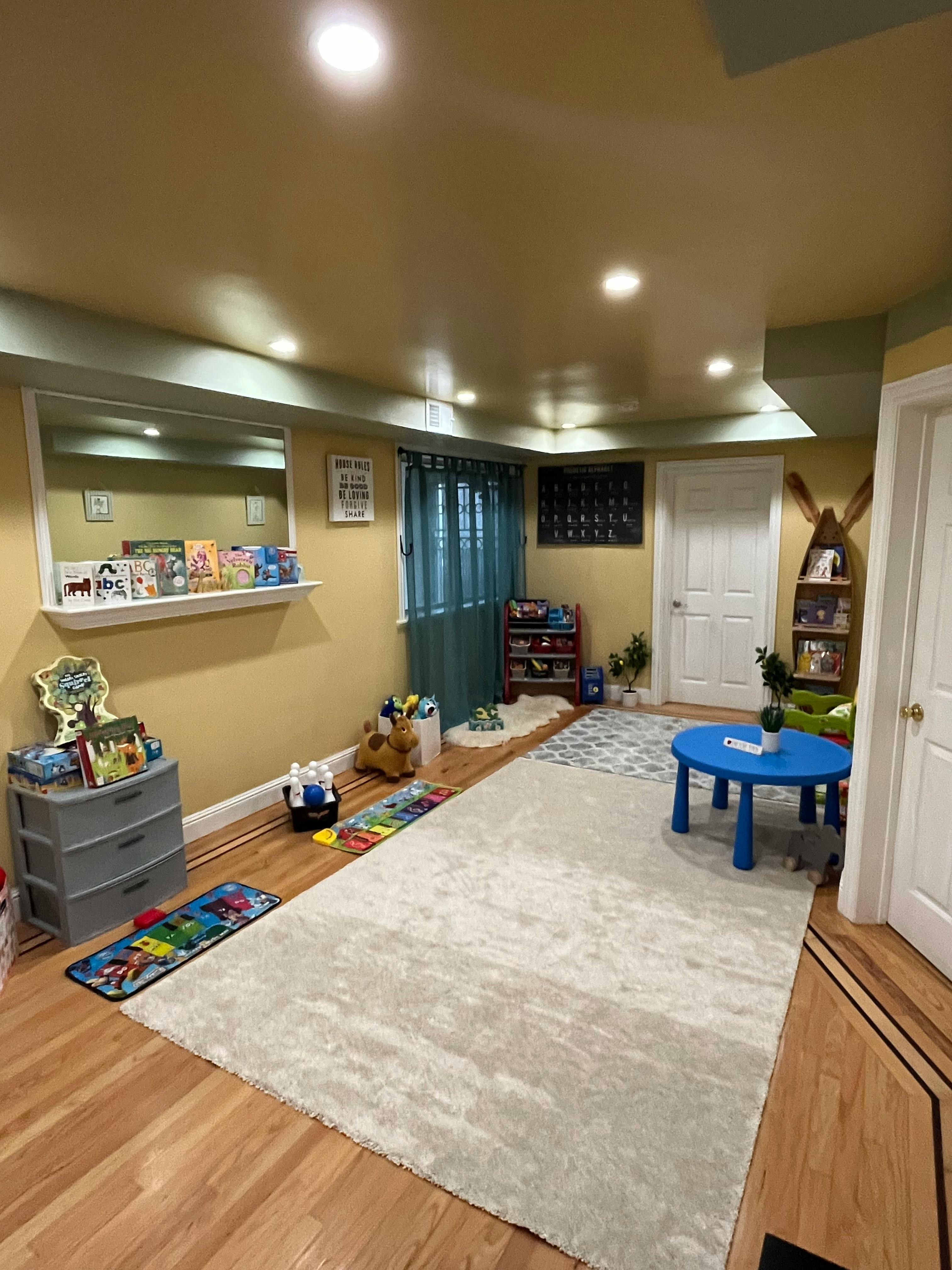 Playroom with a blue table, rugs, and shelves with books and toys