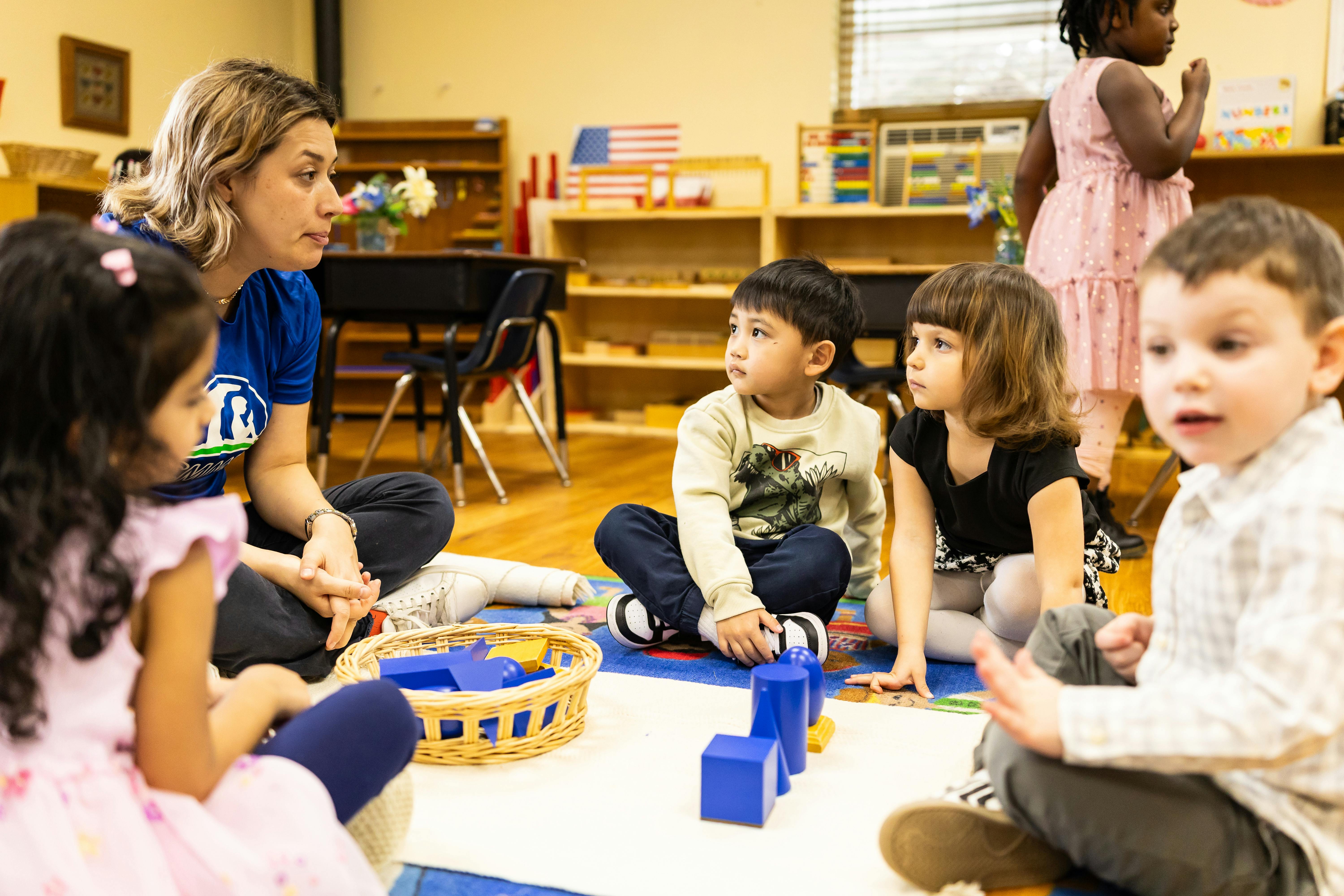 Adult and children sitting on a rug in a classroom, listening