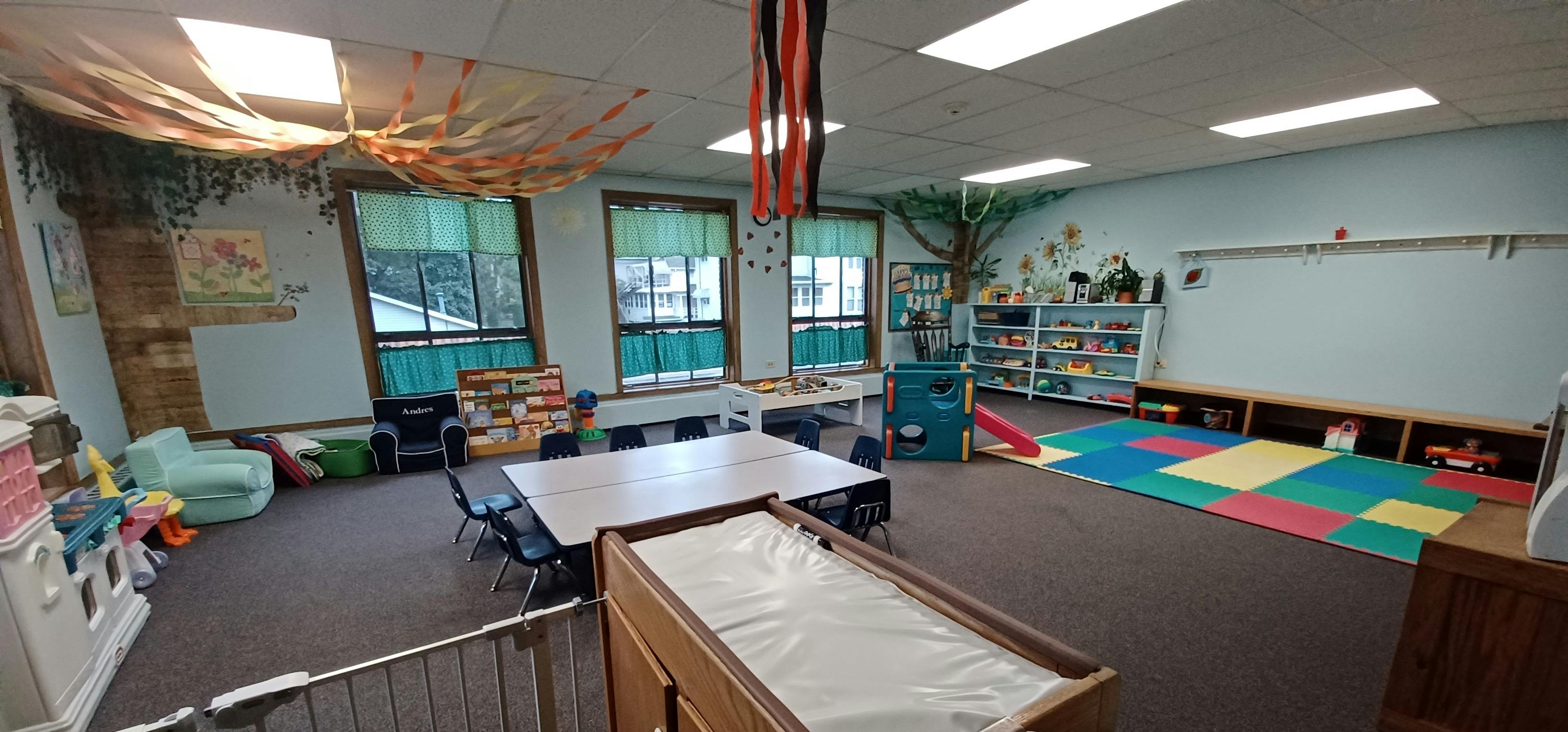 Classroom with tables, chairs, and colorful play mats