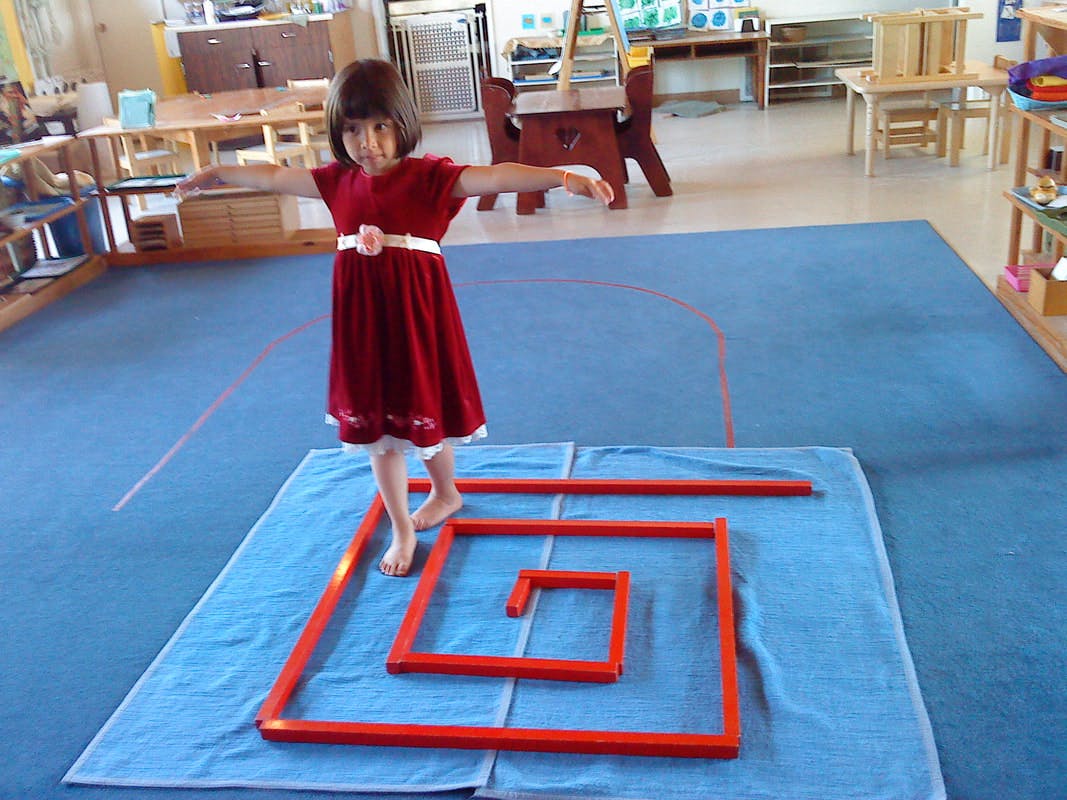 Child balancing on a red square spiral on a blue mat