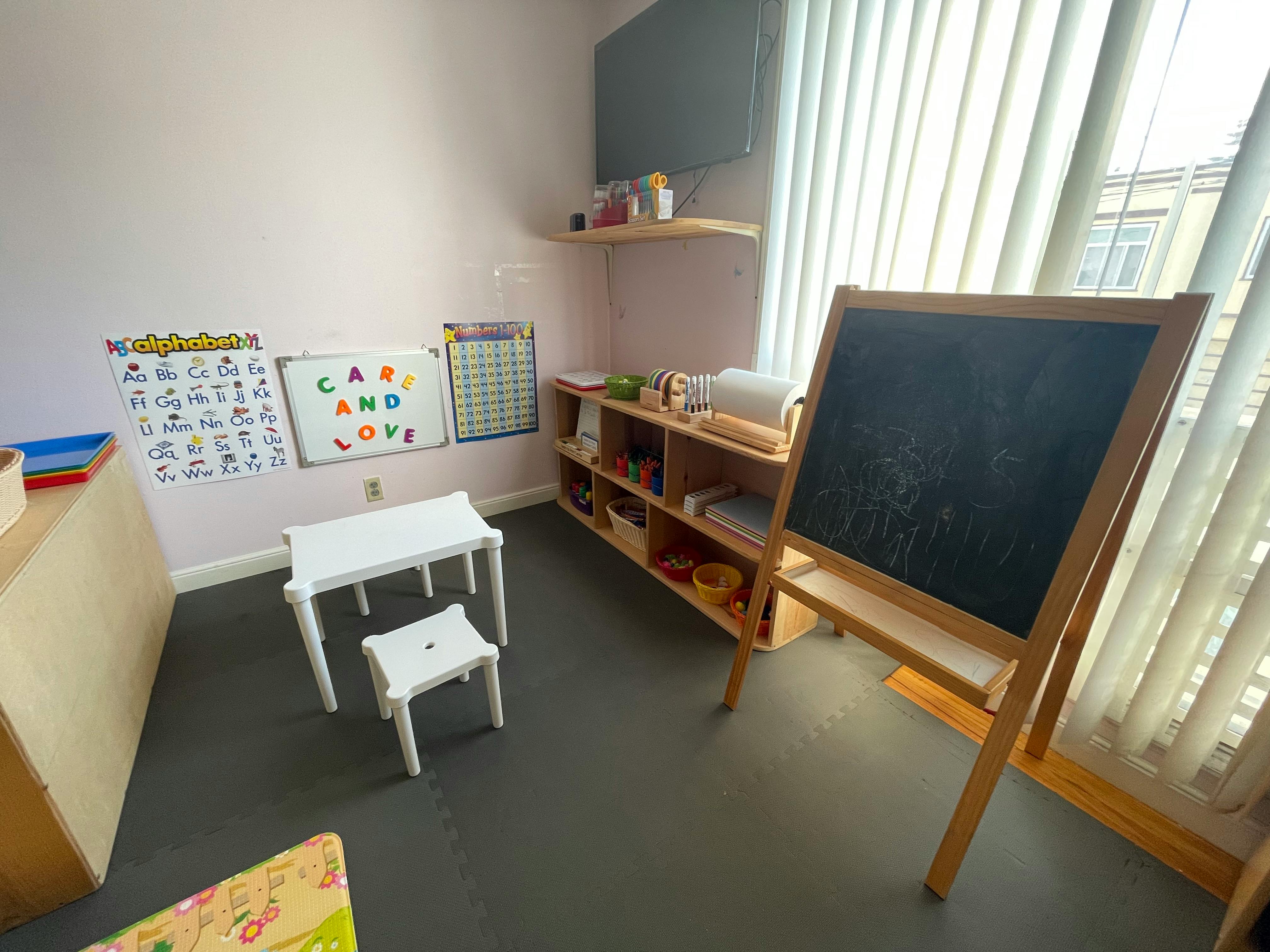 Classroom with small table and chair, shelves, and chalkboard