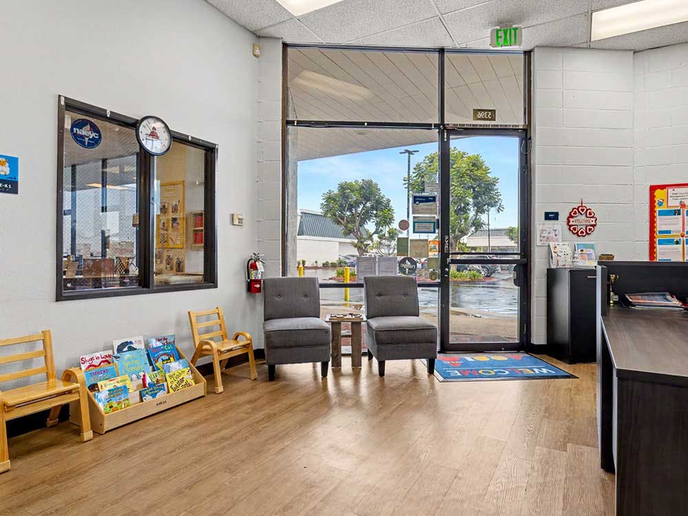 waiting area with two small chairs, a book display, and two upholstered chairs