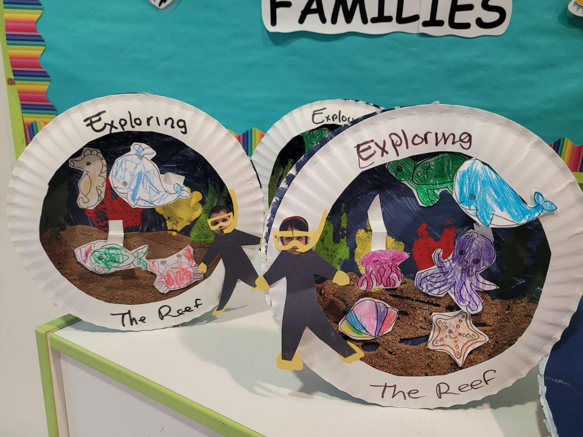 Classroom art project showing paper plate dioramas of underwater reef scenes with cutout sea life