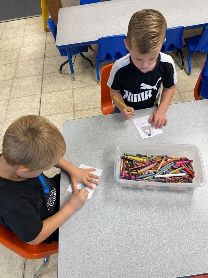 Two children drawing at a table with crayons