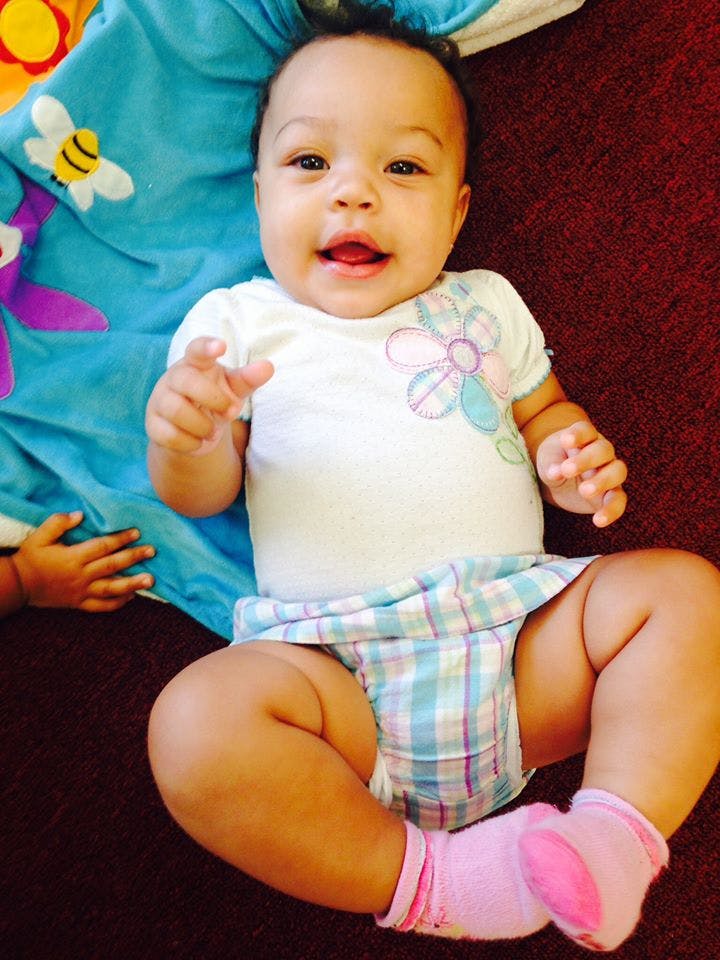 Child in a white shirt with a flower design and plaid shorts