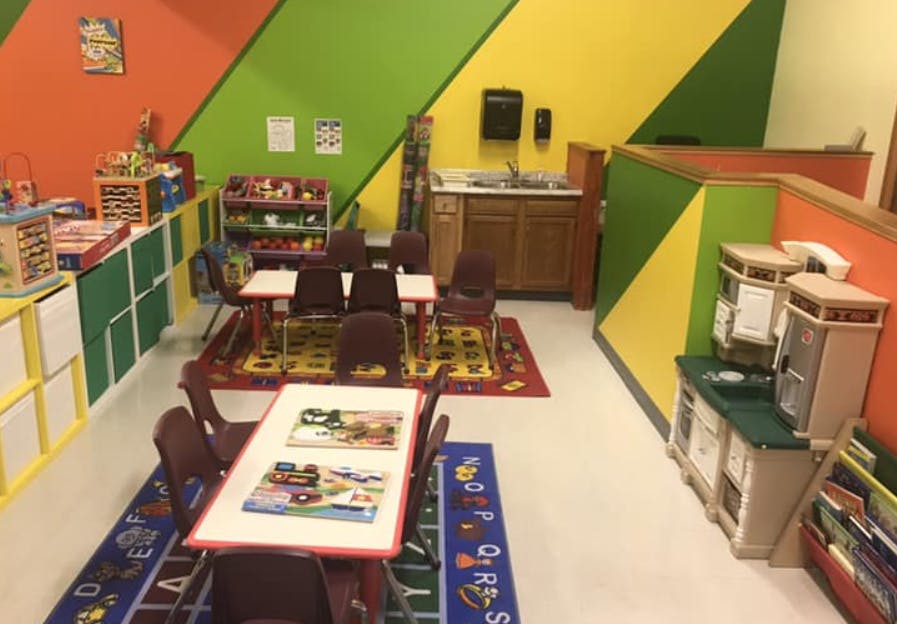 Classroom with small tables and chairs, play kitchen, and colorful walls
