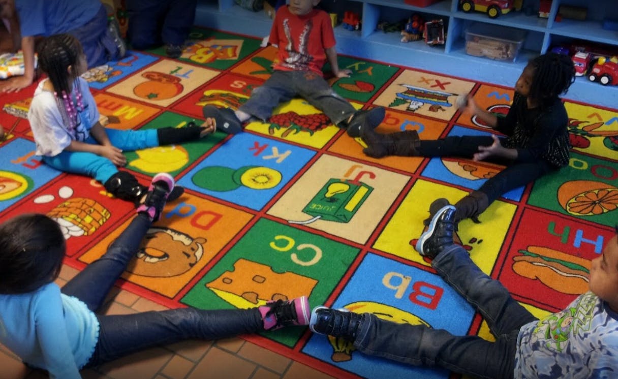 Children sitting on a colorful alphabet rug