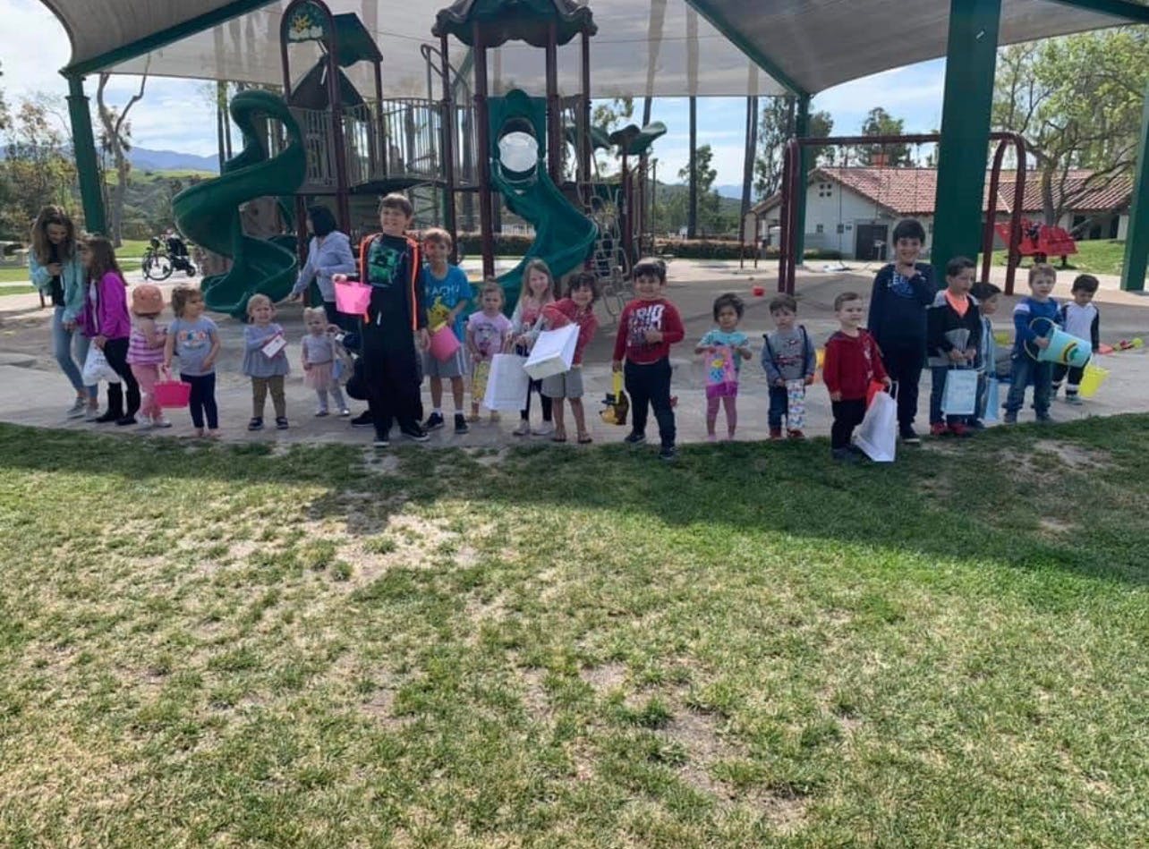 Group of children standing on a playground with baskets and bags