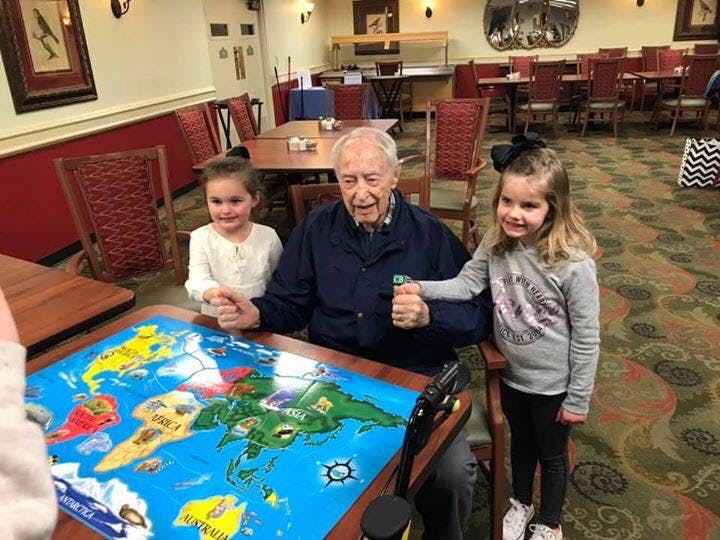 Older person and two children playing a board game with a world map