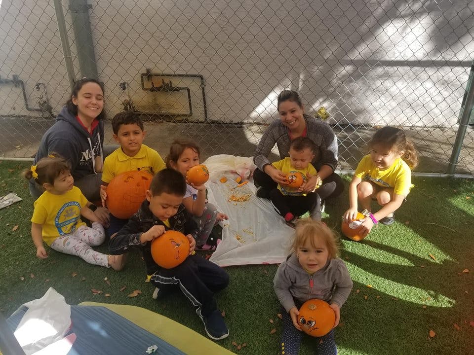 People and children sitting on grass with pumpkins