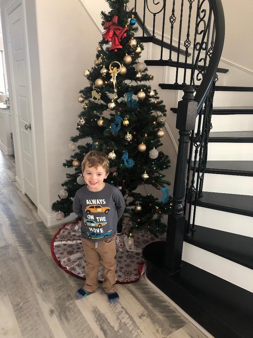 Child standing in front of a decorated Christmas tree