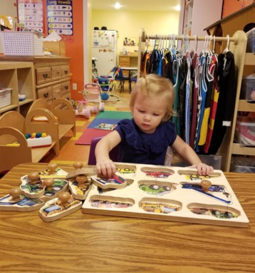 Child playing with a wooden puzzle at a table