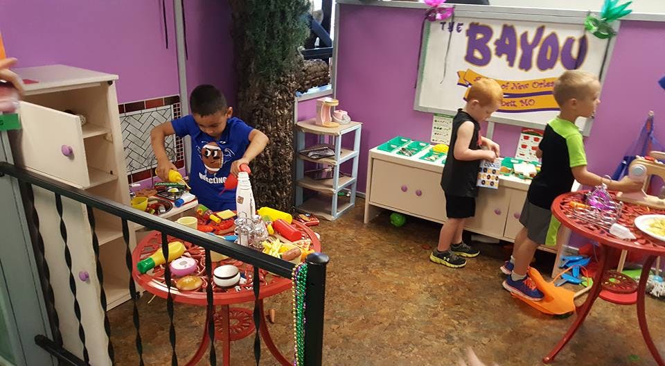 Children playing with toys in a room with a sign that says "Bayou"