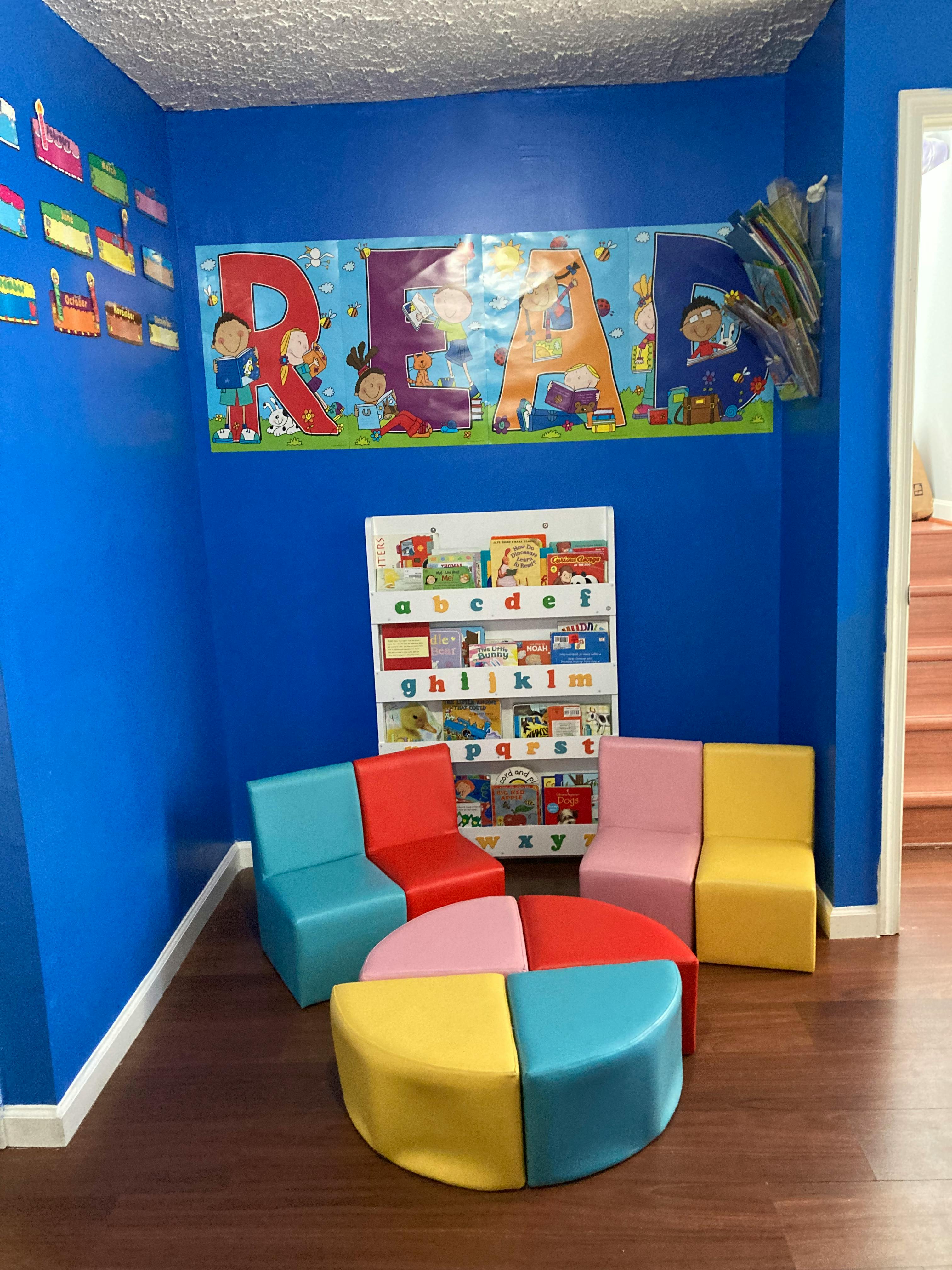 Children's reading nook with colorful chairs, a circular ottoman, and a bookshelf