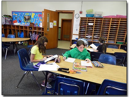 Children writing at desks in a classroom