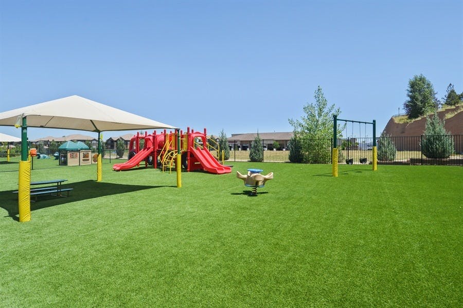 Outdoor playground with red slides, swings, and a covered seating area