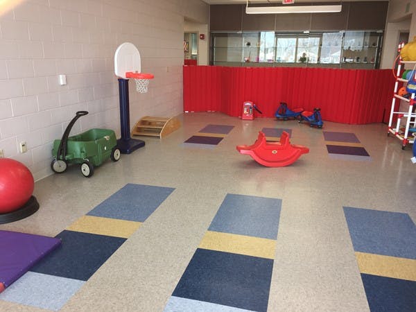 Indoor play area with a basketball hoop, wagon, and red seesaw