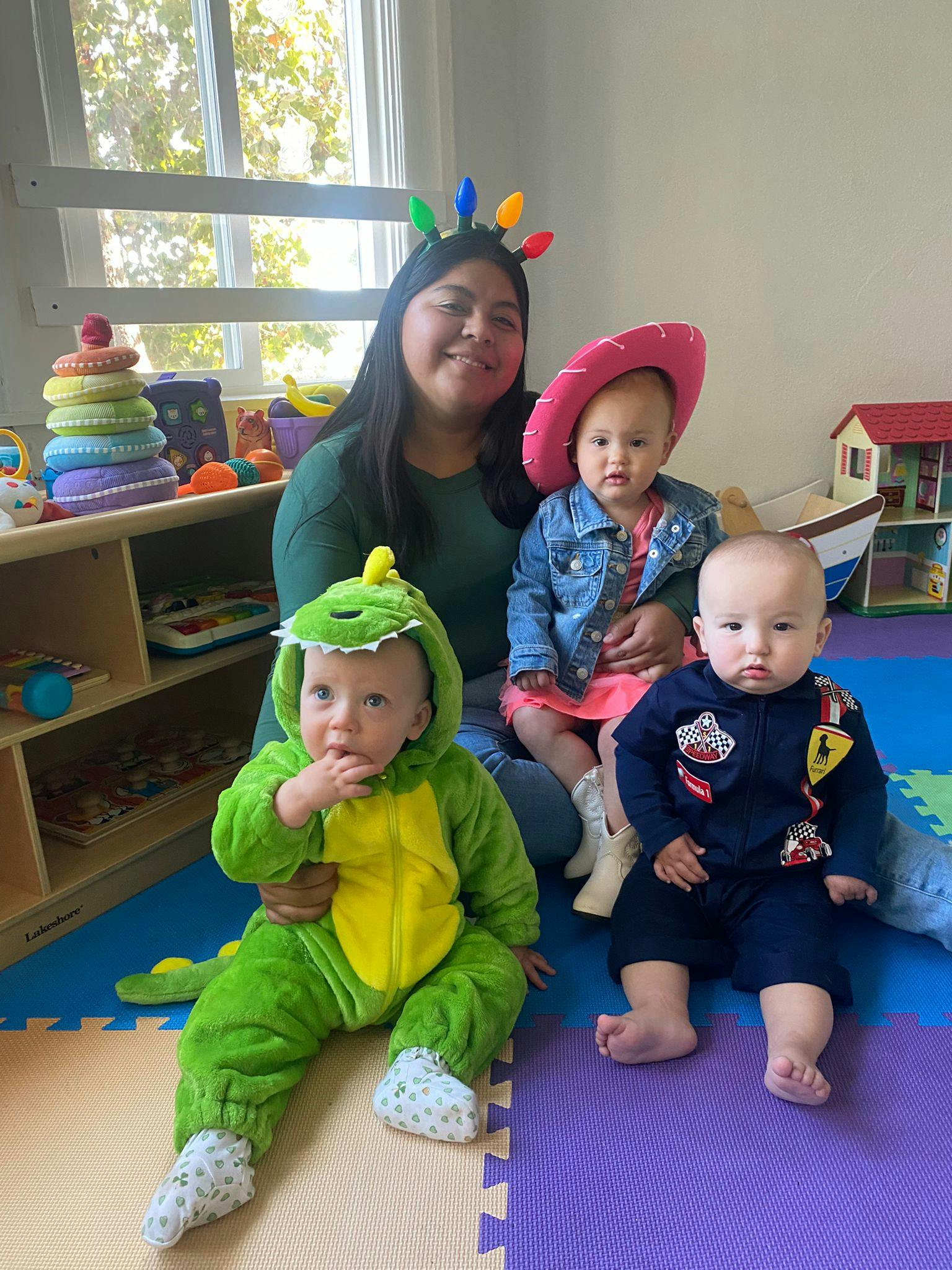 Person with three children, two in costumes, on a playmat