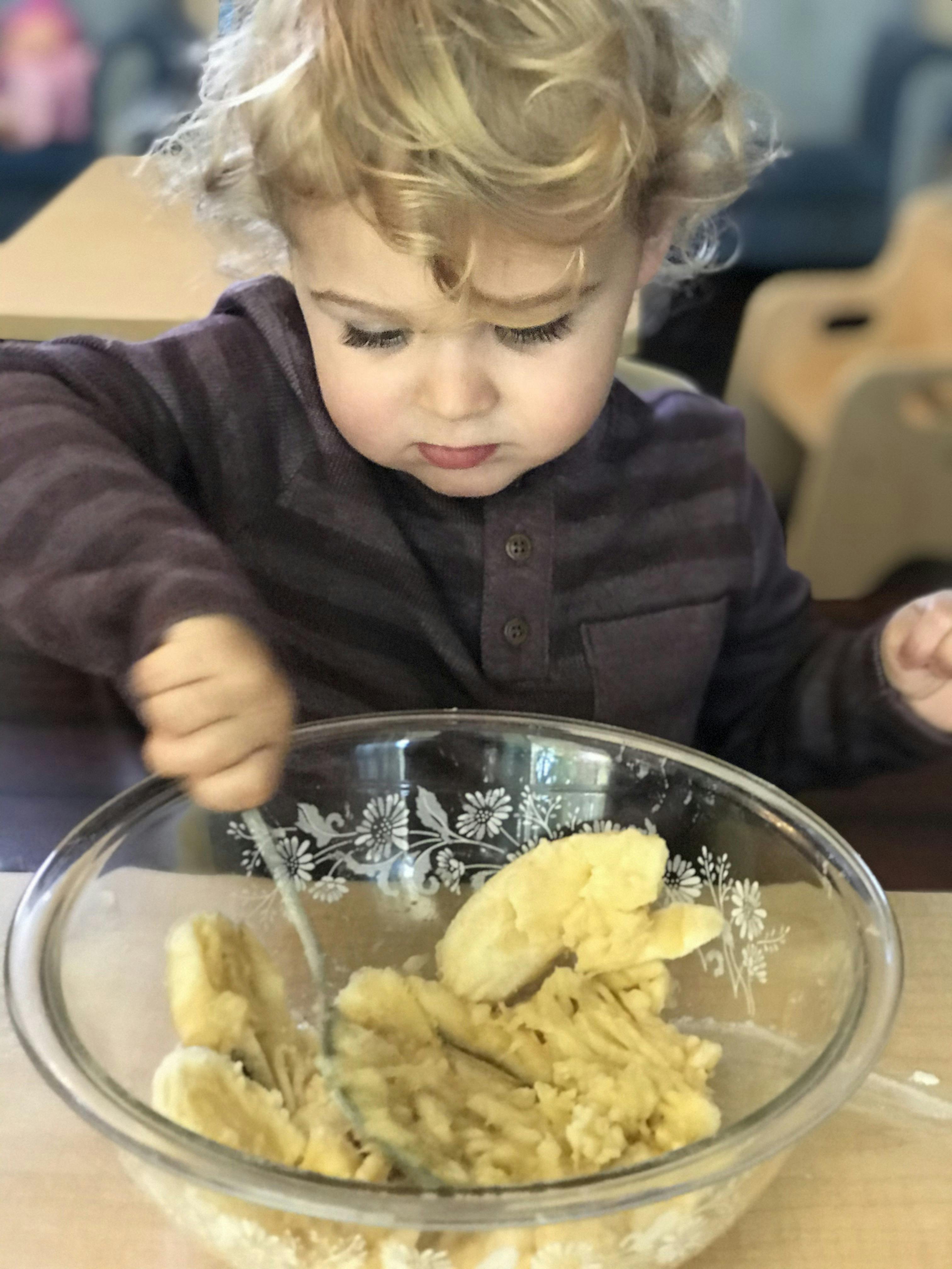 Child mashing bananas in a bowl