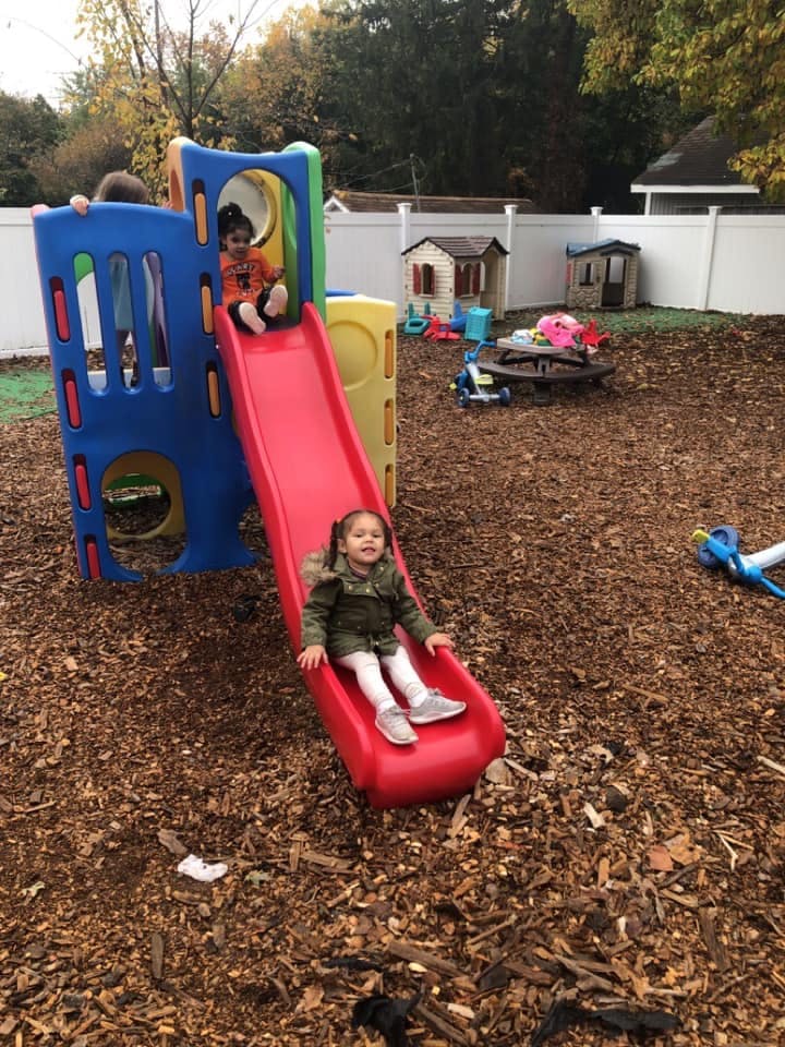Child on a red slide with another child at the top of the play structure