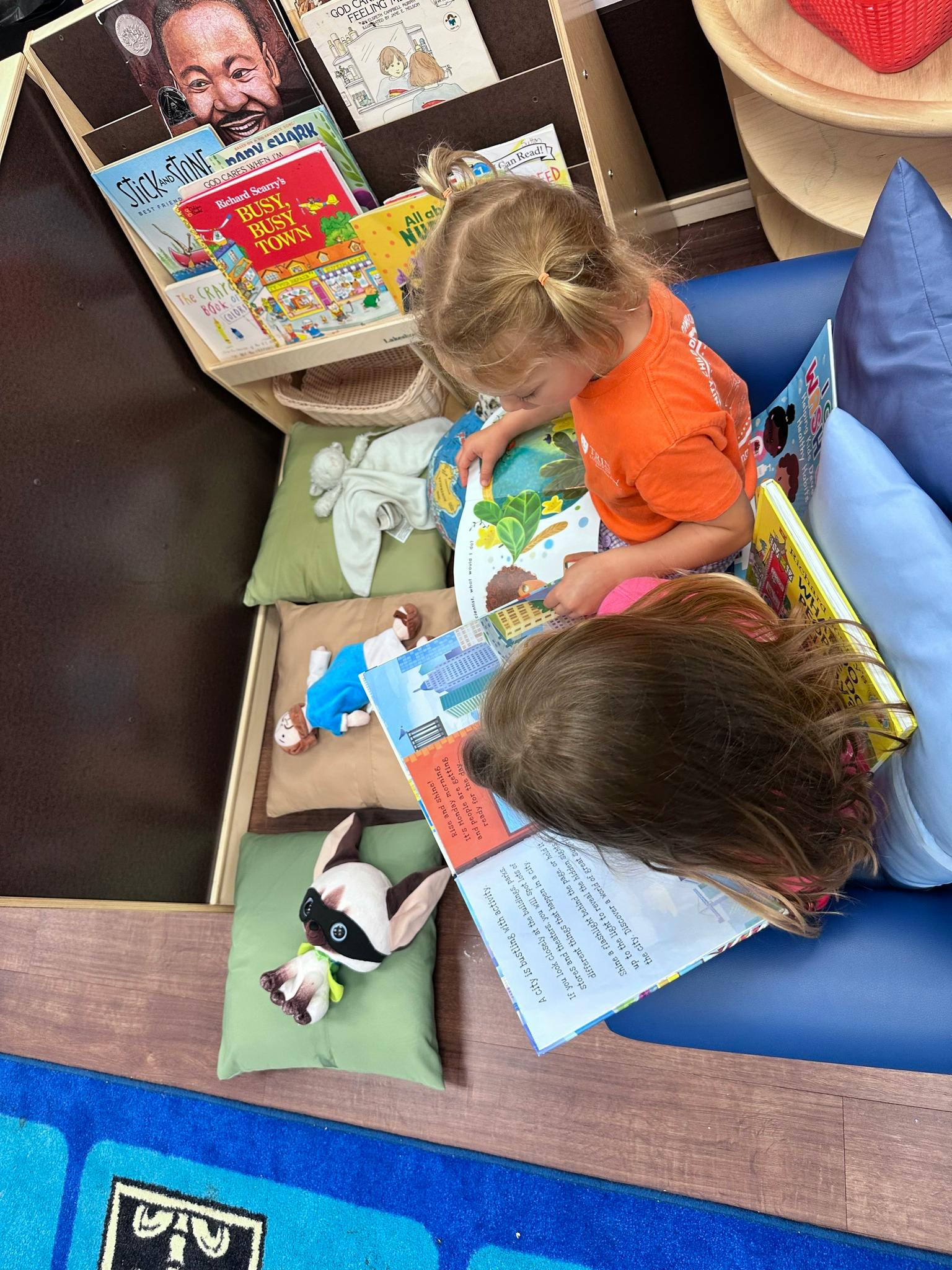 Two children reading books on cushions