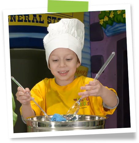 Child in chef hat stirring a pot with utensils