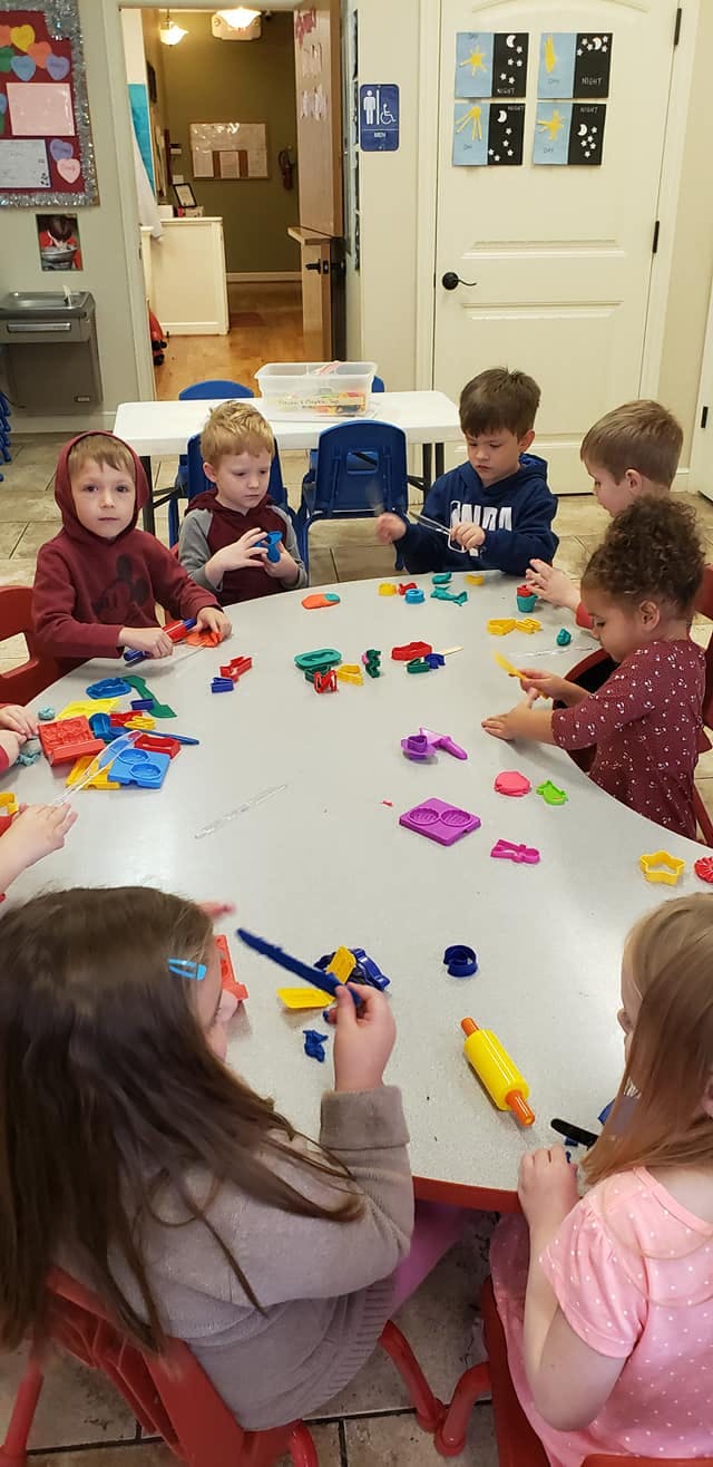 Children playing with colorful toys at a table in a classroom