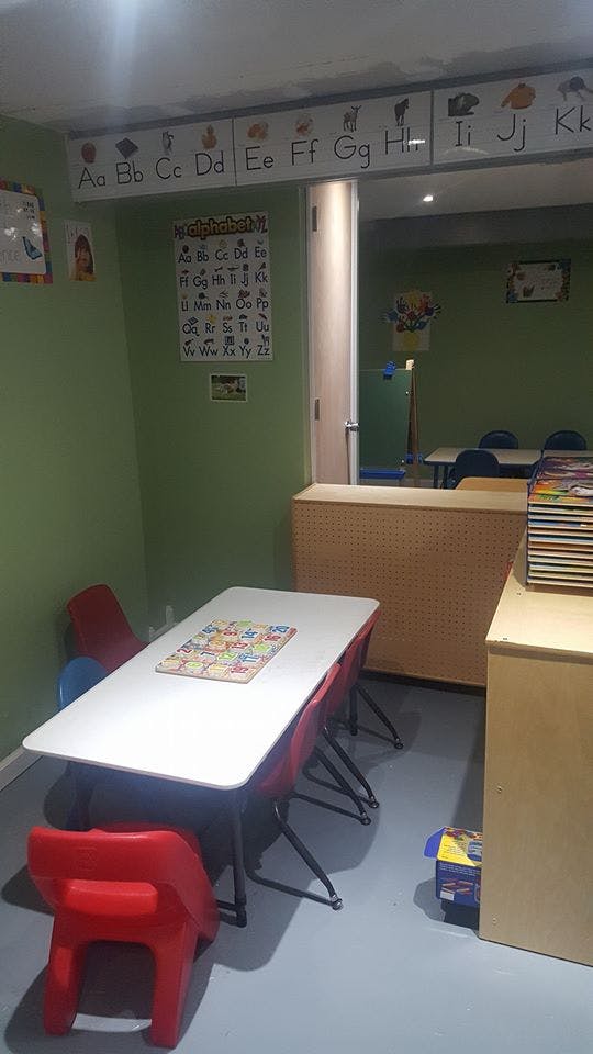 Classroom with small tables and chairs, alphabet charts on the wall
