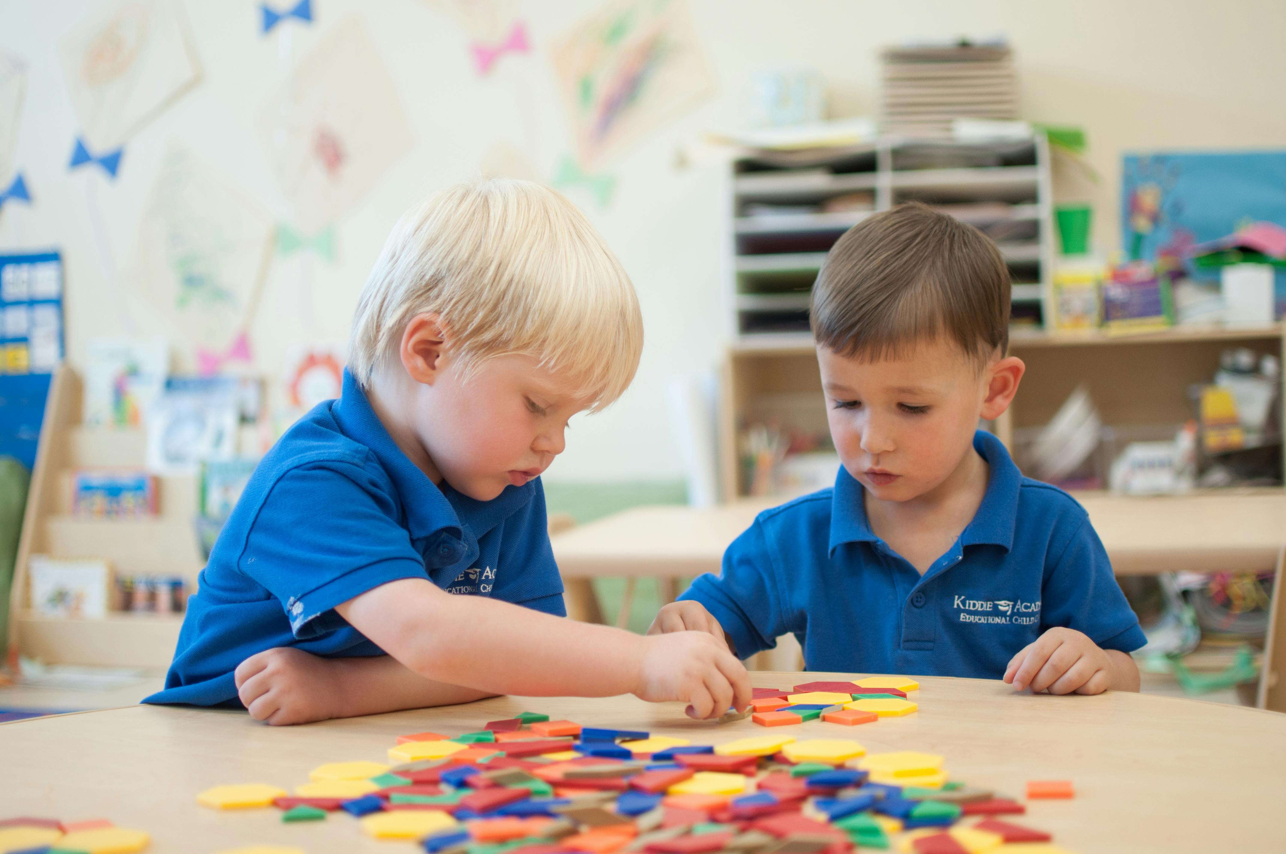 Two children playing with colorful geometric shapes at a table