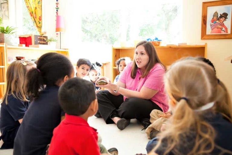 Adult speaking to children sitting on the floor in a classroom