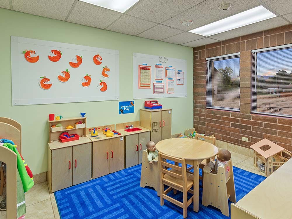 Children's classroom with small tables, chairs, and play kitchen area