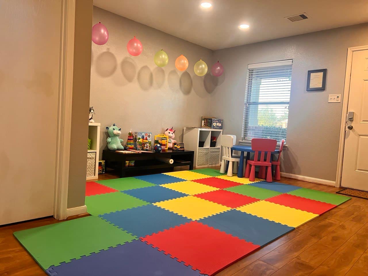Playroom with colorful floor mats, balloons, and small table and chairs