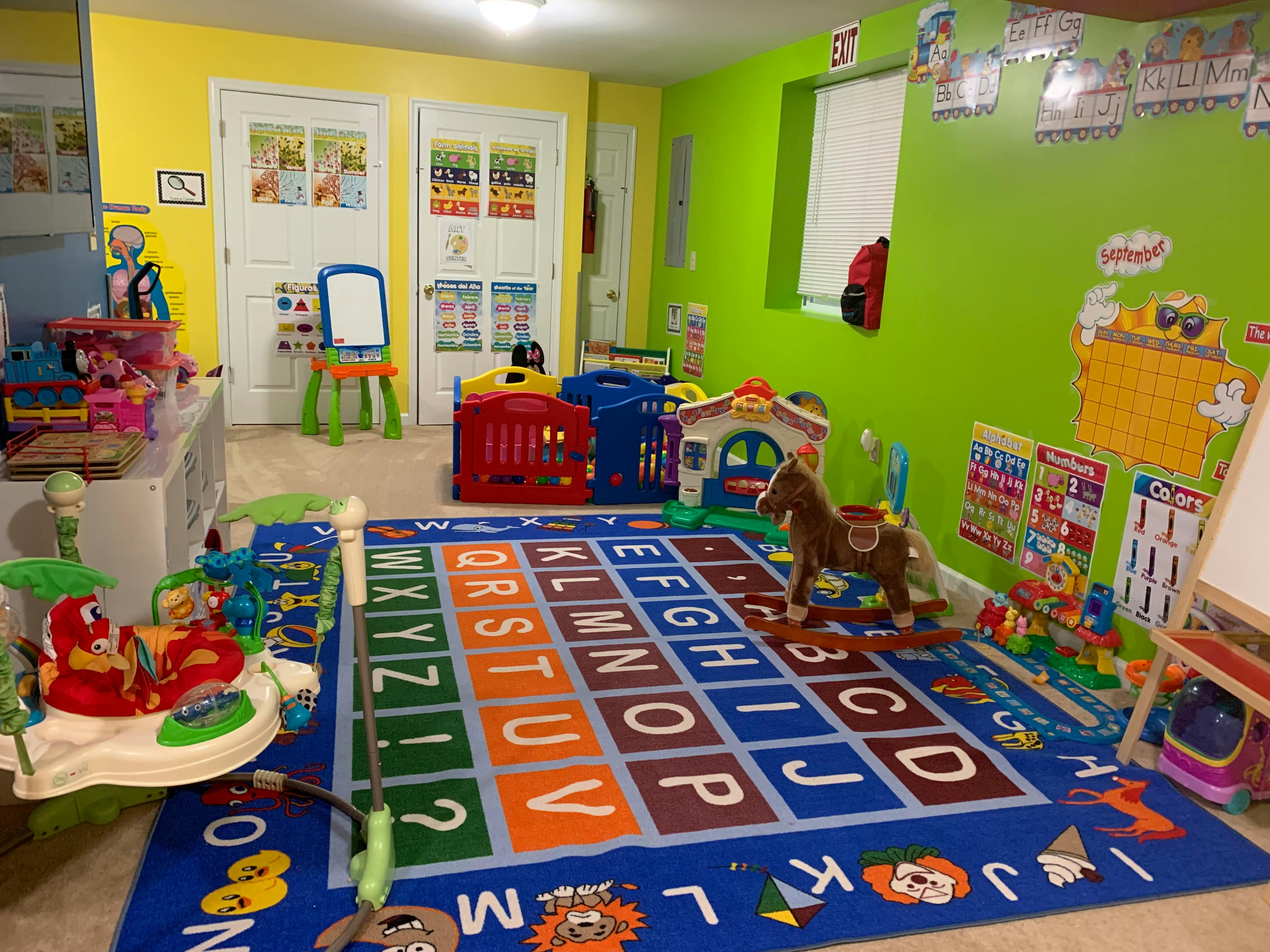Colorful playroom with alphabet rug, various toys, and educational posters on the walls
