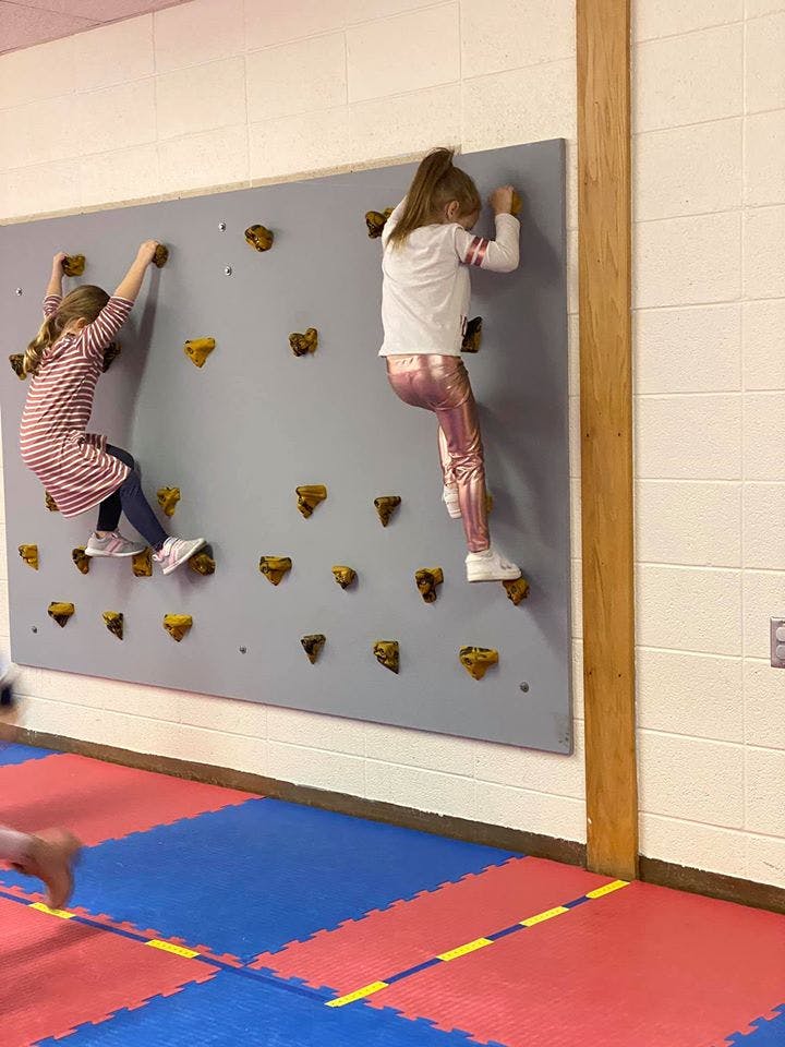 Two children climbing on an indoor rock wall