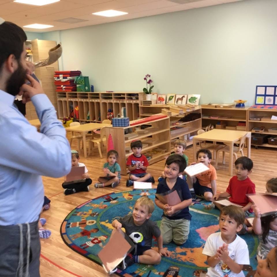 Person speaking to children sitting on a rug in a classroom